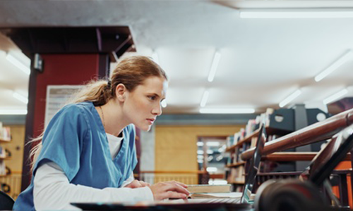 Laptop, woman and medical student in library with study, browsing and research for university exam. Person, reading or learning in college with computer, knowledge or higher education for healthcare.